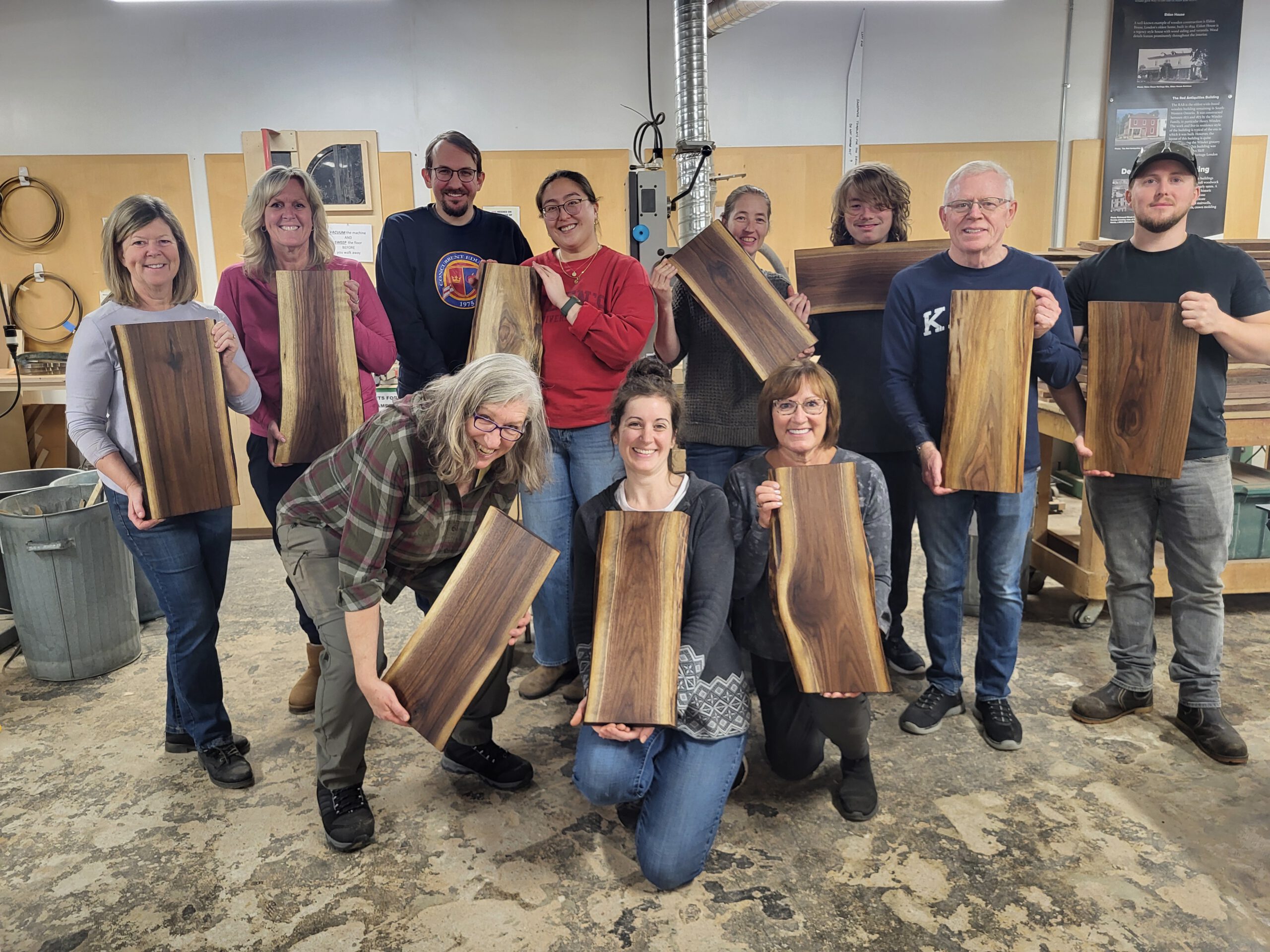 A happy group of workshop students hold their charcuterie boards they made