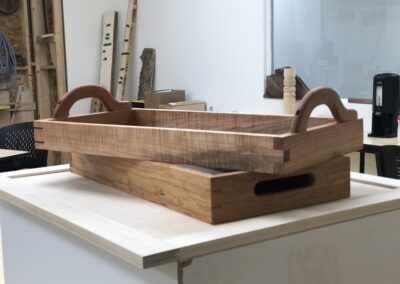 Two carrying trays made from wood in the woodshop on a table in the shop