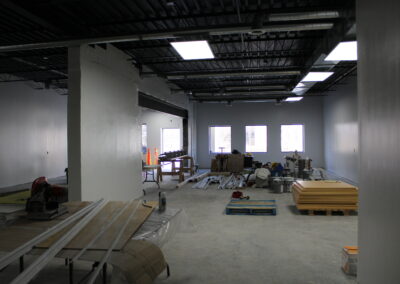 The interior of the woodshop before. Empty room with large metal roof and ventilation units over a concrete floor