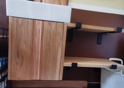 A wooden sink with shelves and pump created by a woodshop member