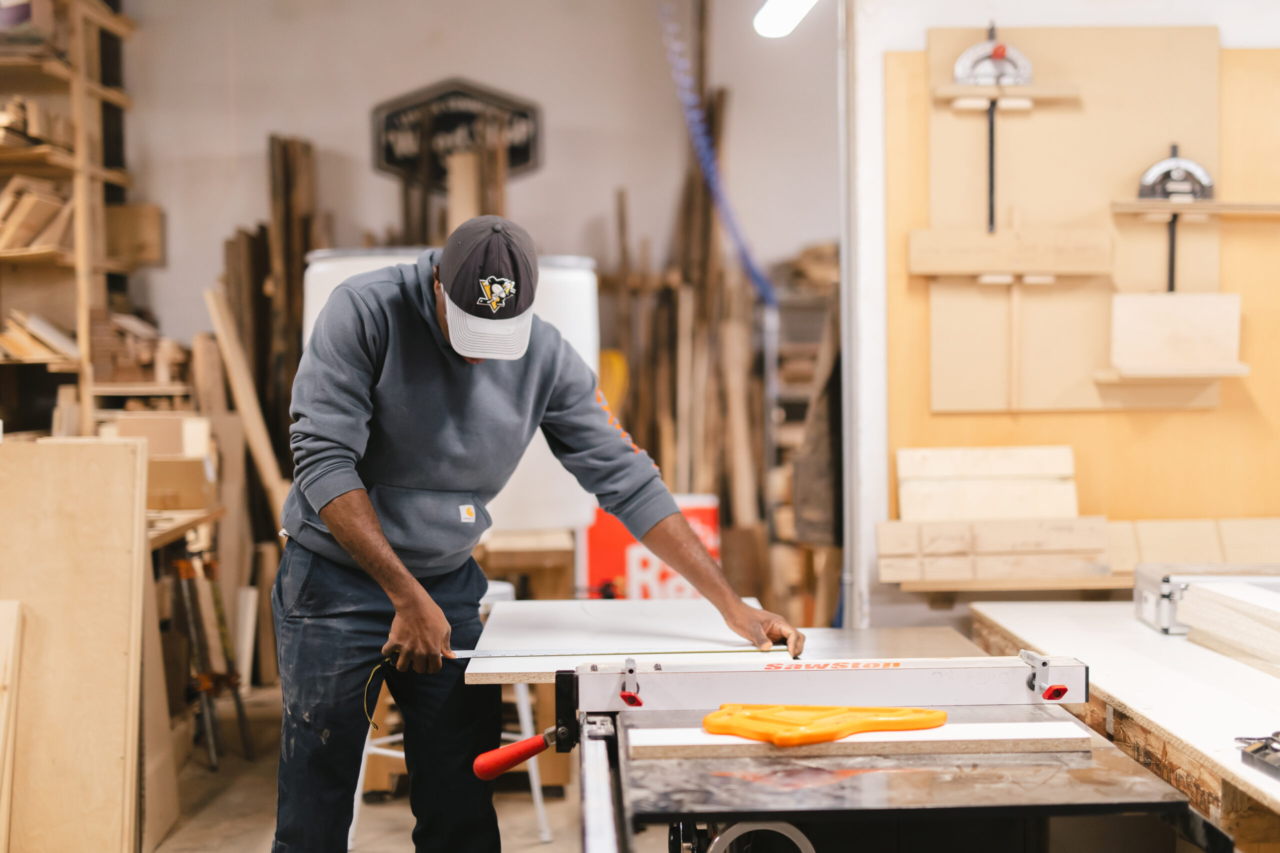 A woodshop member works in the woodshop to cut boards